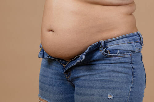 Woman with flabby belly thick sides showing waist unzipped jeans blue color sudden weight gain visceral fat body positive tight little clothes need wardrobe change